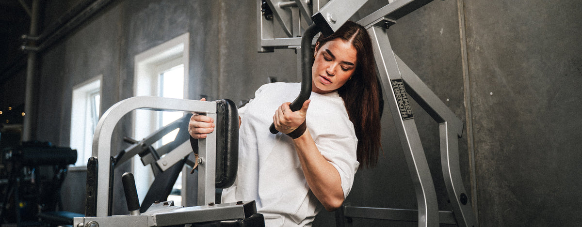 Kvinde bruger StrapIt løftestropper til rows i fitnesscenter - MakeIt Danmark